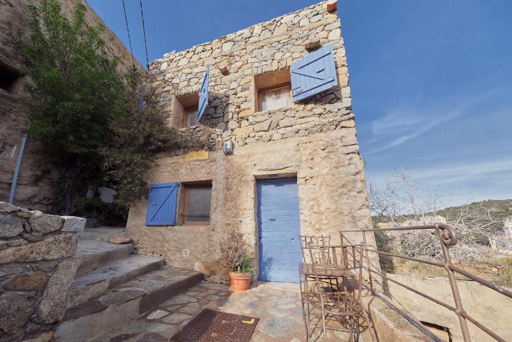 a stone house with a blue door and stairs at CASA MIA - Maison et chambres à louer à Corbara in Corbara