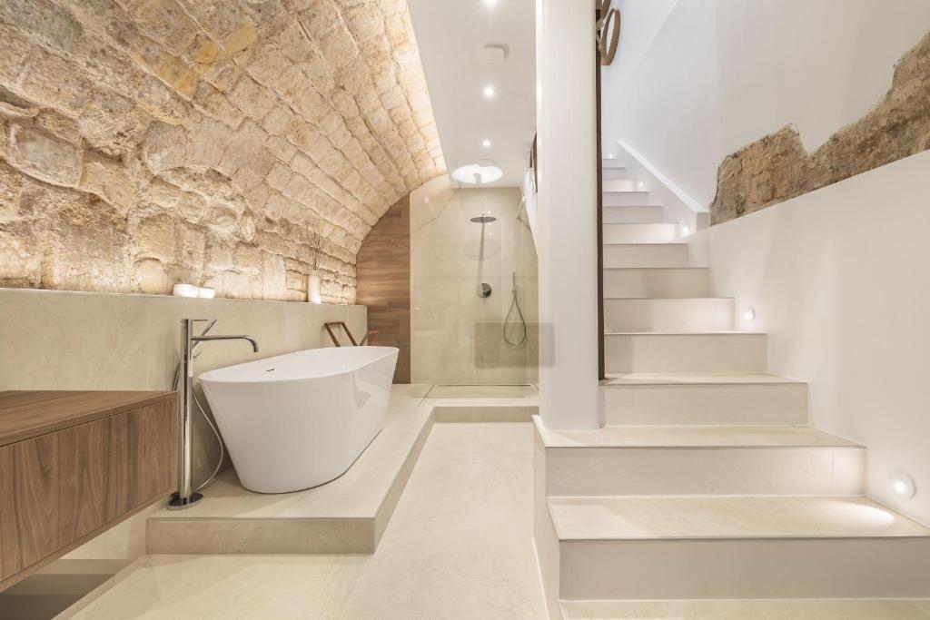 La salle de bains est pourvue d'une baignoire à côté d'un mur en pierre. dans l'établissement Bulle, à Paris