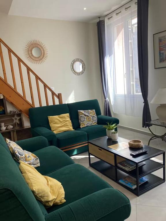 un salon avec un canapé vert et une table dans l'établissement Gîte l'Olivier, à Bollène