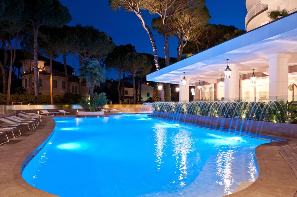 una piscina iluminada por la noche en Hotel Belvedere, en Milano Marittima