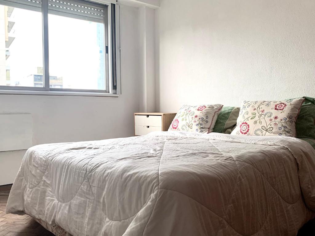 a white bedroom with a bed with a window at Departamento Moreno in Rosario