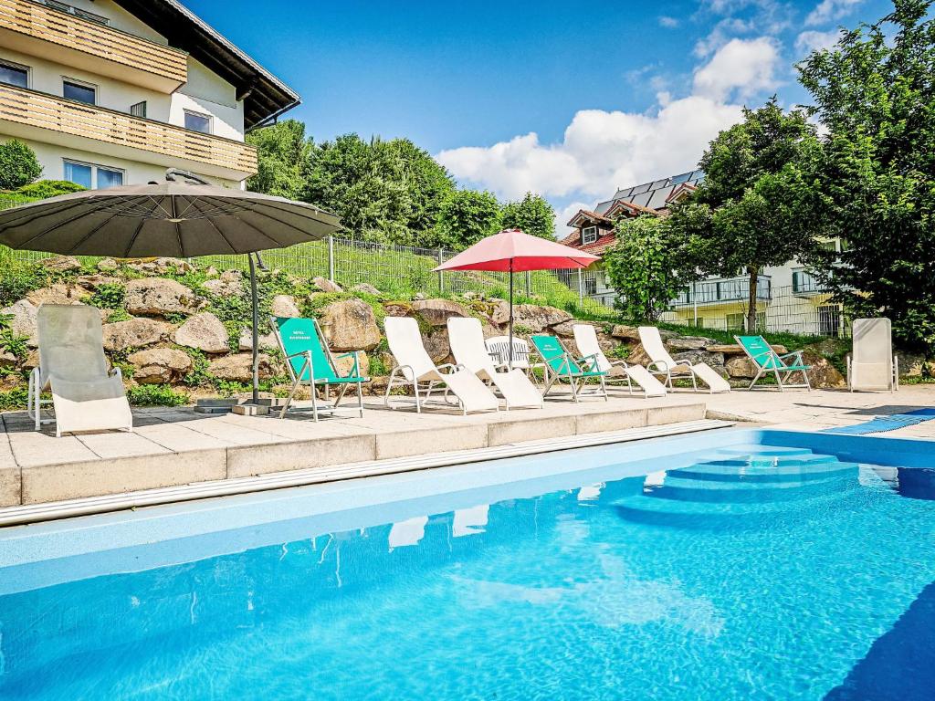 a group of chairs and umbrellas next to a swimming pool at Holiday Home Marianne by Interhome in Baierweg
