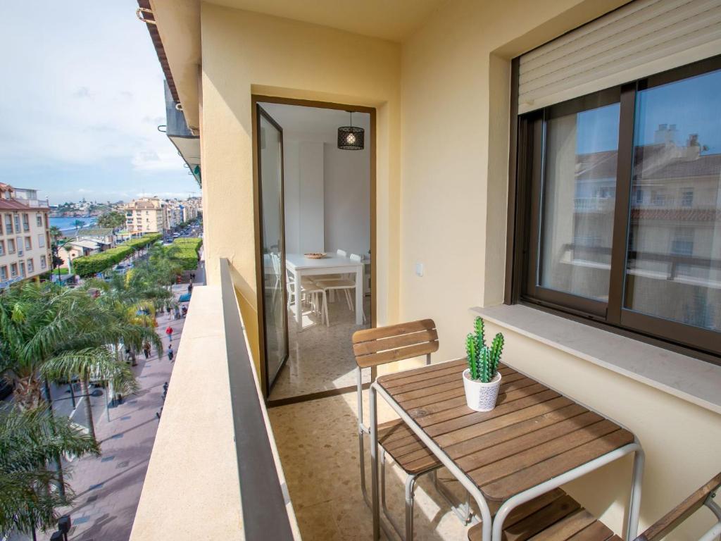 Un balcón con una mesa y sillas de madera y una ventana. en Apartment Ercén by Interhome, en Rincón de la Victoria