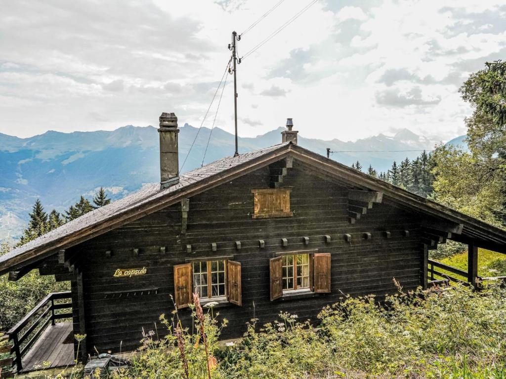 an old wooden house with mountains in the background at Chalet La Capsule by Interhome in Les Collons