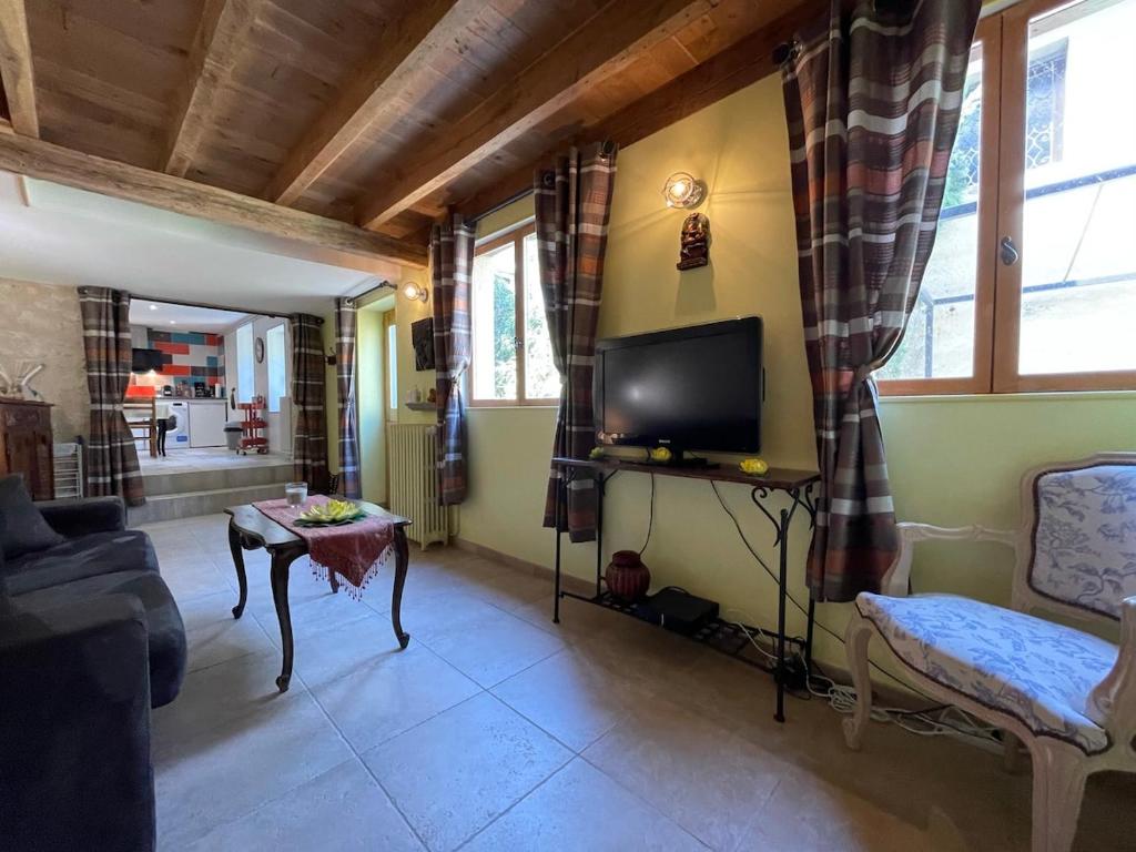 un salon avec une télévision, un canapé et une table dans l'établissement gîte des martinets and its corner of greenery, à Amboise