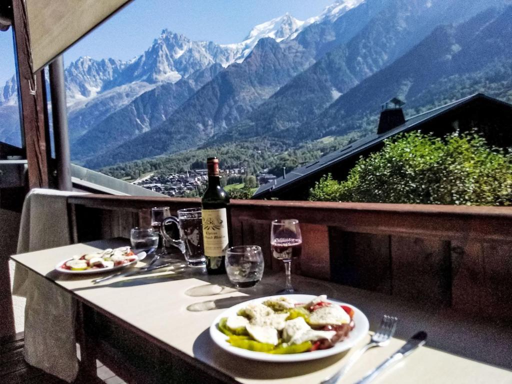 - une table avec deux assiettes de nourriture et une bouteille de vin dans l'établissement Apartment Les Grands Balcons by Interhome, aux Houches