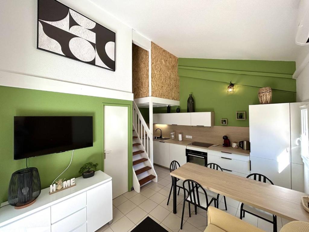 - une cuisine et une salle à manger avec des murs verts et une table dans l'établissement Pavillon climatisé proche plage avec piscine à Argelès-sur-Mer - FR-1-388-227, à Argelès-sur-Mer
