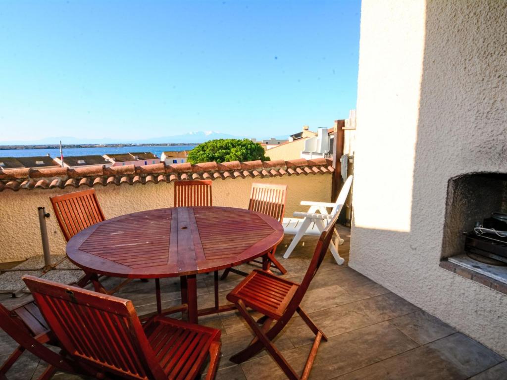 une table et des chaises en bois sur une terrasse avec une cheminée dans l'établissement Apartment Coudalère-Guadeloupe-16 by Interhome, au Barcarès