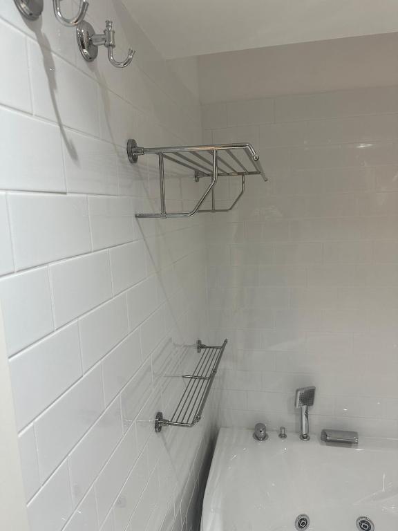 a white tiled bathroom with a tub and a shelf at Apartment DB in Split
