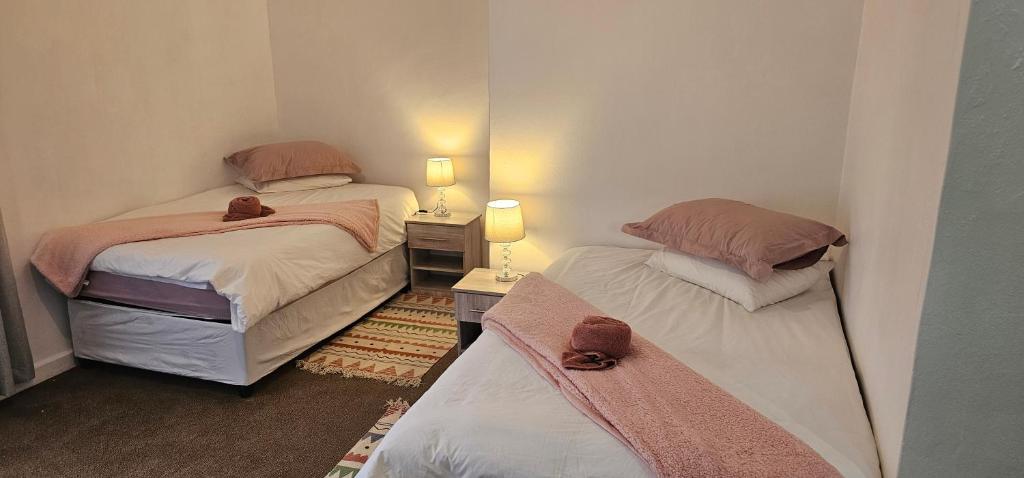 two twin beds in a small room with two lamps at The Haven Guesthouse 2 in Estcourt