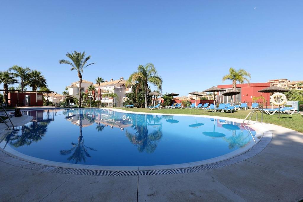 a large swimming pool in a resort with palm trees at 105 Welcoming Andalusian Style 2 Bed Apartment With Views of Miraflores Golf in Sitio de Calahonda