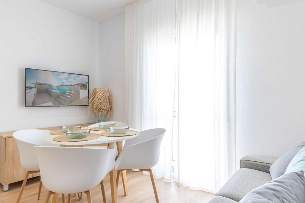 a white living room with a table and chairs at APARTAMENTOS CARMEN in Maro