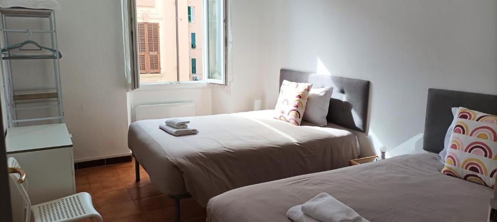 a bedroom with two beds and a window at Casa Aprosio, appartamento luminoso in centro a Ventimiglia, a 5 min dal mare e dal treno in Ventimiglia