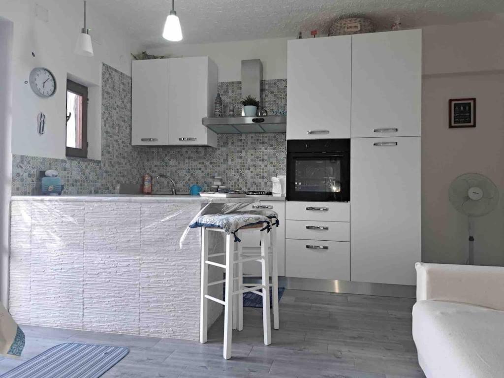 een keuken met witte kasten en een barkruk bij Antema in Scario