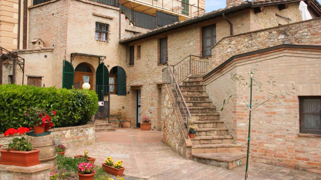 a brick building with stairs and flowers in a courtyard at Il Pozzo Di Sant'Andrea in Siena