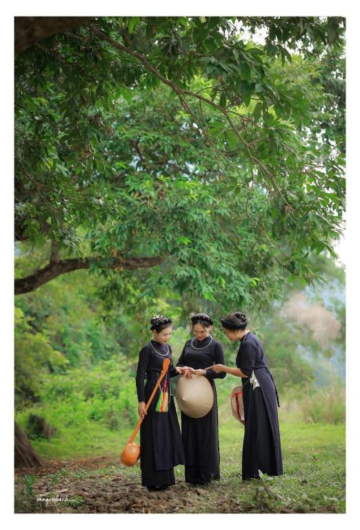three women in traditional clothing holding a drum at Ba Be Retreat in Bak Kan
