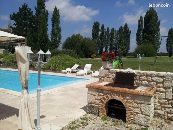 - une cheminée en pierre installée à côté d'une piscine dans l'établissement Maison en pierre 6 personnes, à Montaut