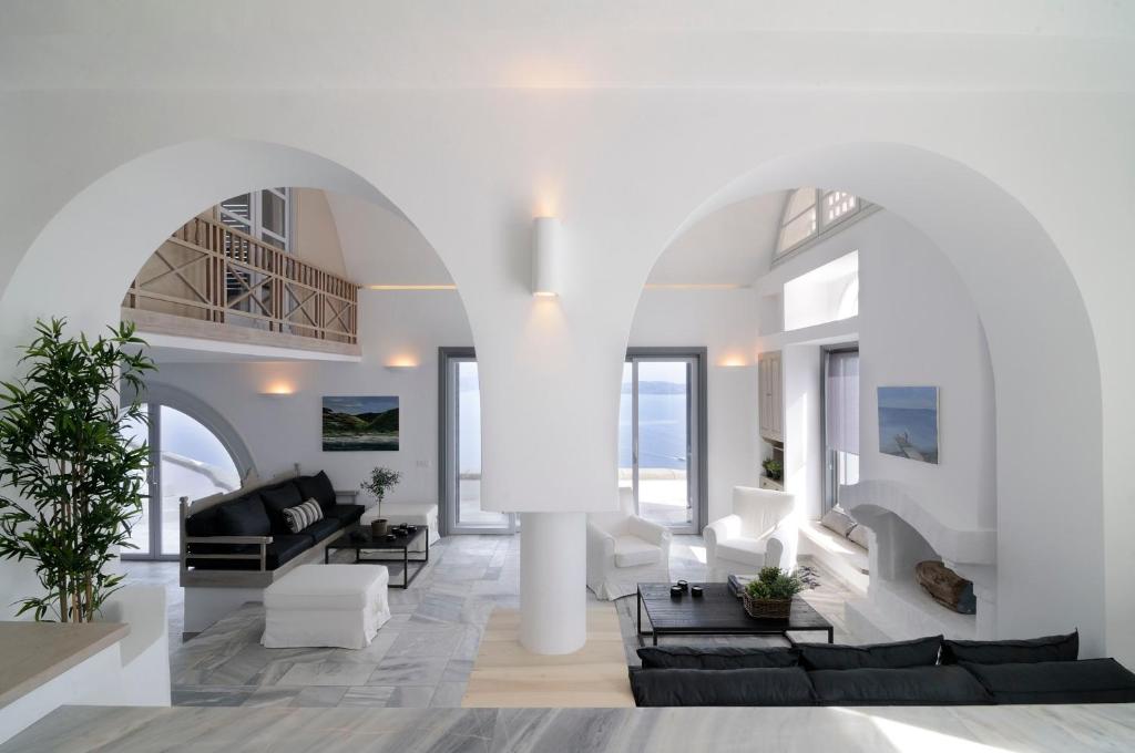 una sala de estar con muebles blancos y un gran arco en Beautiful Oia Villa, en Oia