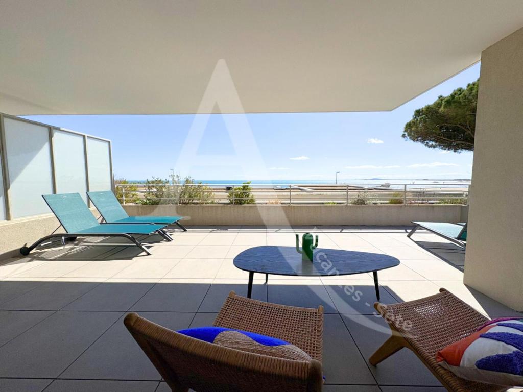 un patio avec une table et des chaises sur un balcon dans l'établissement FRONT DE MER 98 M², 3 CHAMBRES, TERRASSE 90 M², à Sète