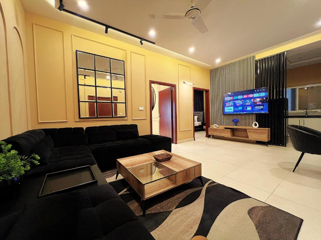 a living room with a black couch and a tv at Central City 2BHK by StayMehman in Rawalpindi