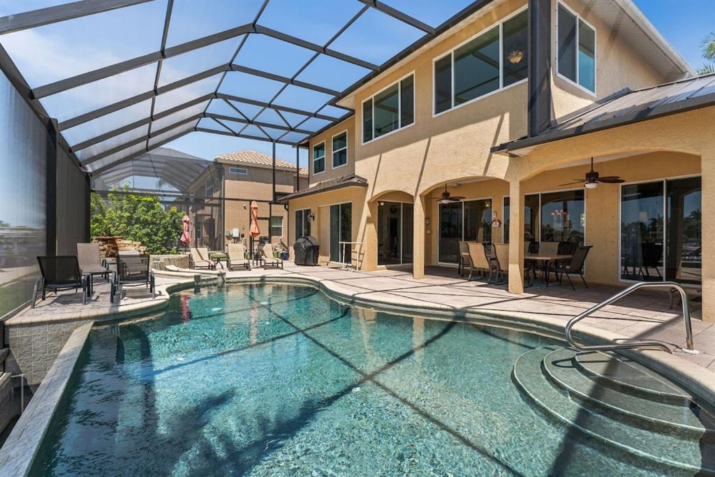 ein Haus mit einem Swimmingpool vor einem Gebäude in der Unterkunft Villa Estelle - Huge lake front Villa in Cape Coral