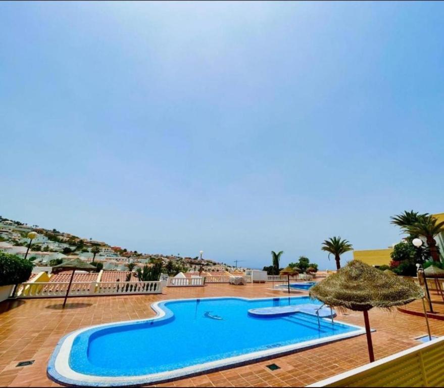 una gran piscina con sombrilla y el océano en Las Americas Holiday Studio, en Adeje