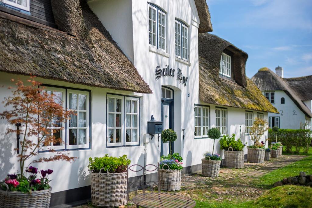 カイトゥムにあるBoutiquehotel Seiler Hof Keitumの鉢植えの植物が置かれた茅葺き屋根の小屋の列