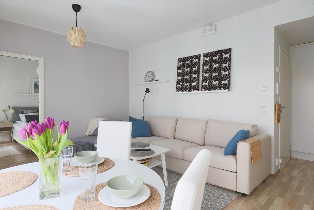 a living room with a white couch and a table at Fredika, modern 1br,Tripla Pasila prime location, gym, parking, train station near in Helsinki