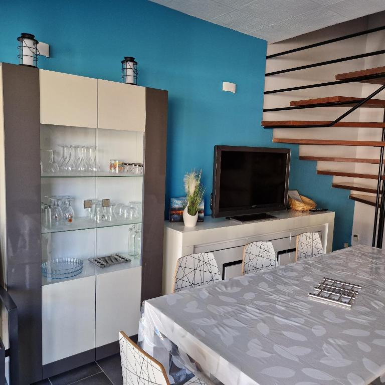 une salle à manger avec une table et une télévision dans l'établissement Location Bord de mer, villa de vacances 6-8 personnes - jardin, à Valras-Plage