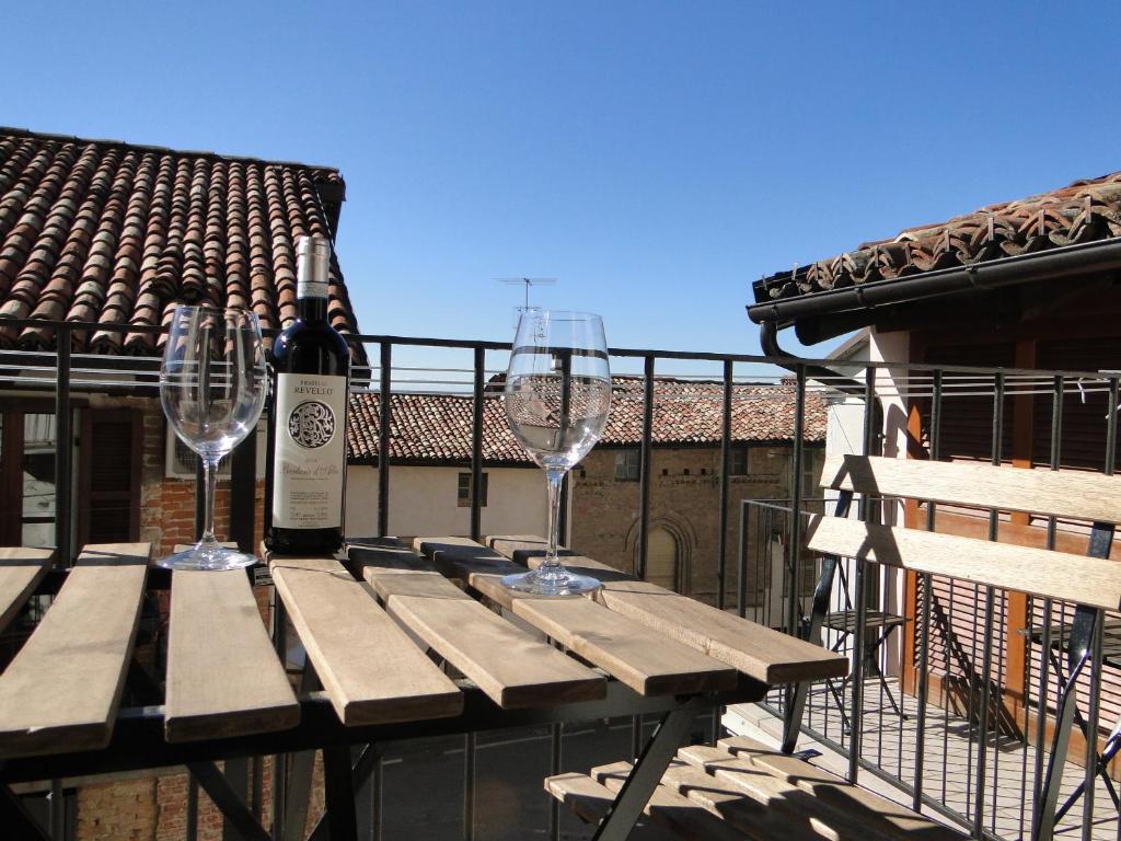 a wooden table with two wine glasses and a bottle of wine at Di-vinodormire in La Morra