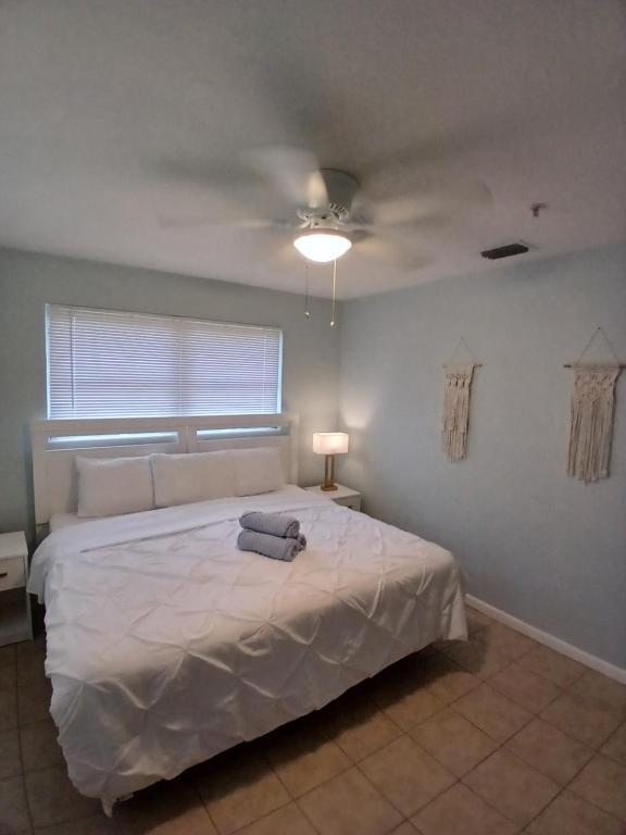 een slaapkamer met een wit bed met een plafondventilator bij 4 BR 2 BA Near the Beach and Intracoastal Walk to everything in Riviera Beach