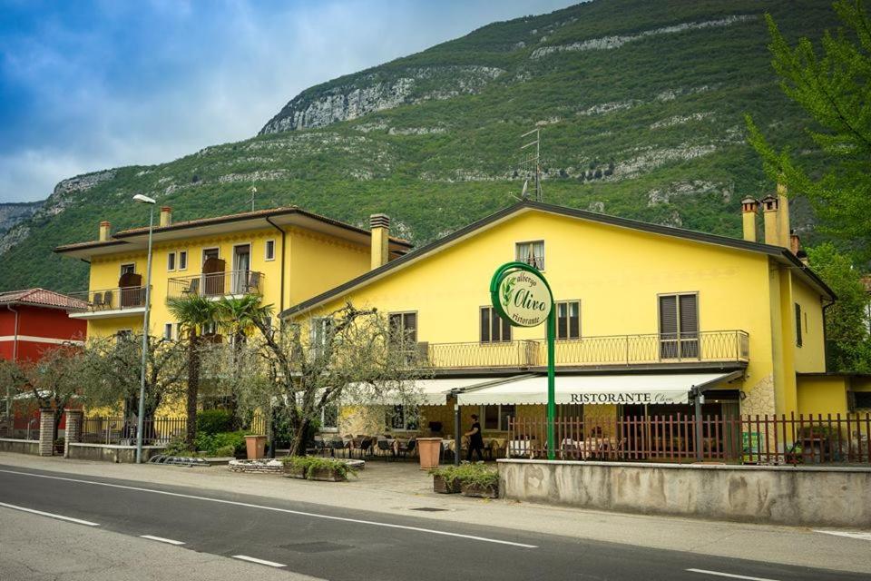 a yellow building on the side of a street with a mountain at Albergo Olivo in Belluno Veronese