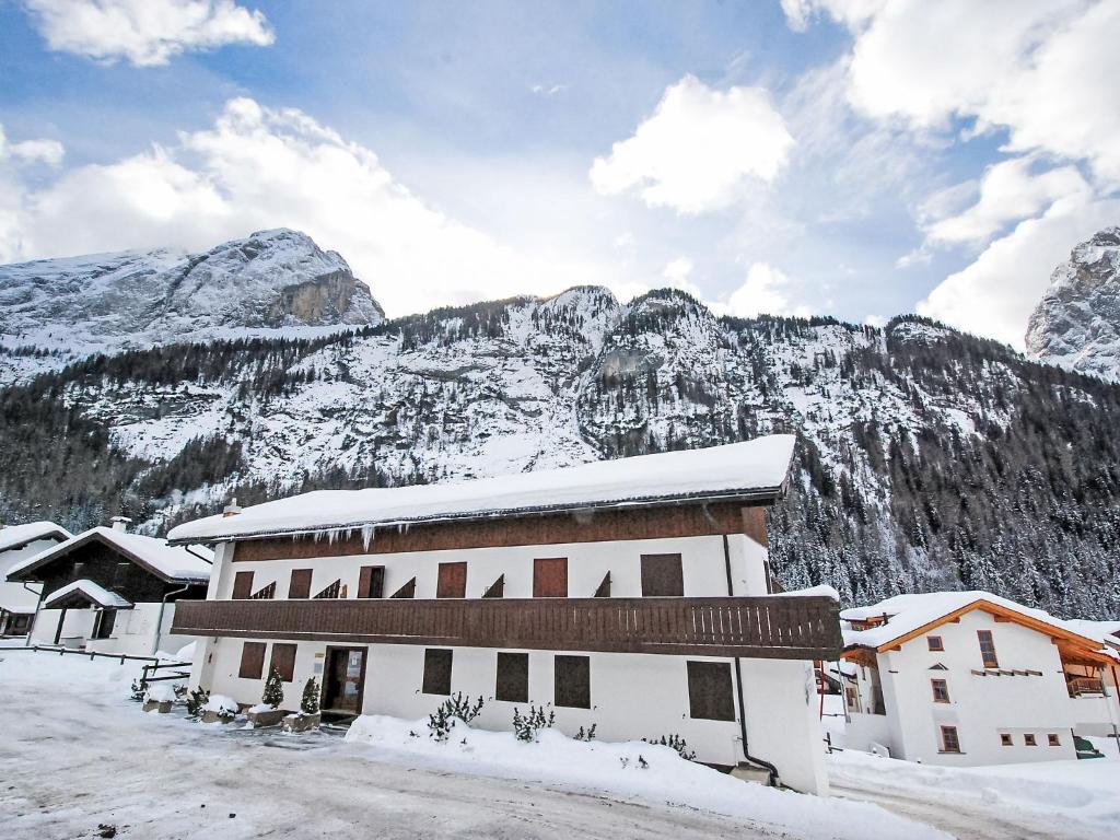 a building covered in snow with mountains in the background at Apartment Penia 2-3 by Interhome in Canazei