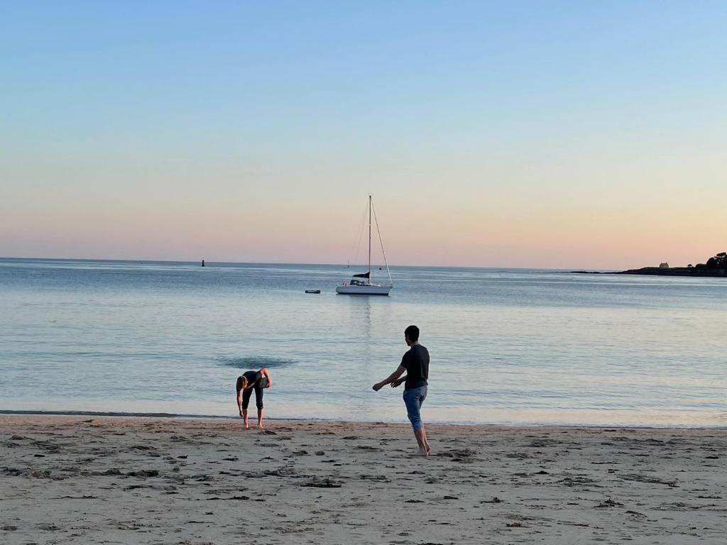 zwei Personen am Strand mit einem Boot im Wasser in der Unterkunft Une pause à Bénodet in Bénodet