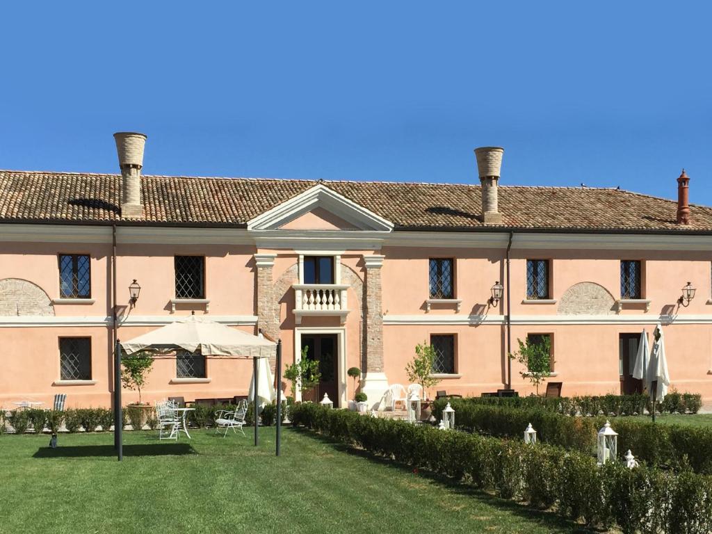 Agriturismo Villa Anconetta في Loreo: مبنى وردي كبير مع حديقة أمامه