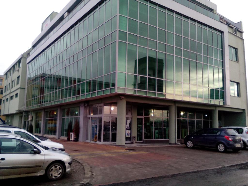 een groot glazen gebouw met auto's geparkeerd voor het bij Office Center and Showroom in Boergas