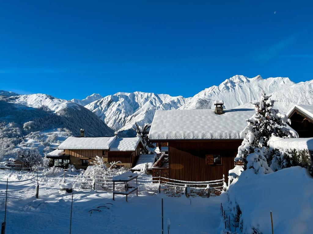 une maison couverte de neige avec des montagnes en arrière-plan dans l'établissement Chalet Marmotte, à Saint-Martin-de-Belleville