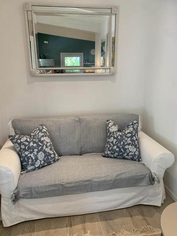 ein Sofa im Wohnzimmer mit Spiegel in der Unterkunft Le Petit Chene in Le Castellet