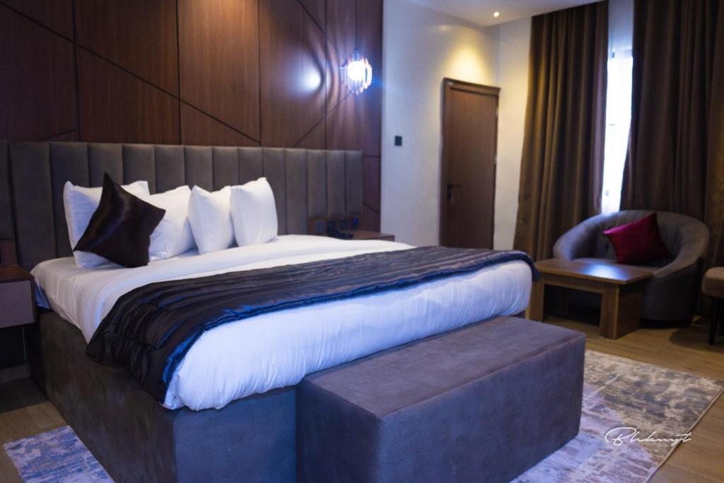 阿沙巴DavMich Hotel的配有一张大床和一把椅子的酒店房间