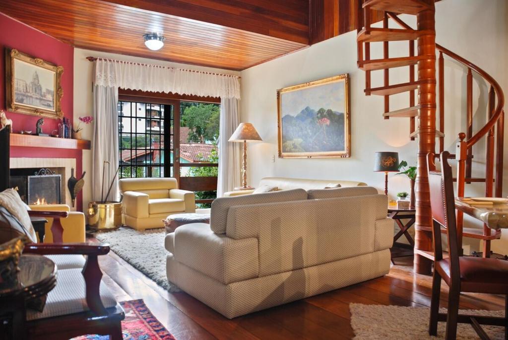 un salon avec un escalier et un canapé dans l'établissement Capivari - Lareira - Estilo Clássico de Casa de Campo, à Campos do Jordão