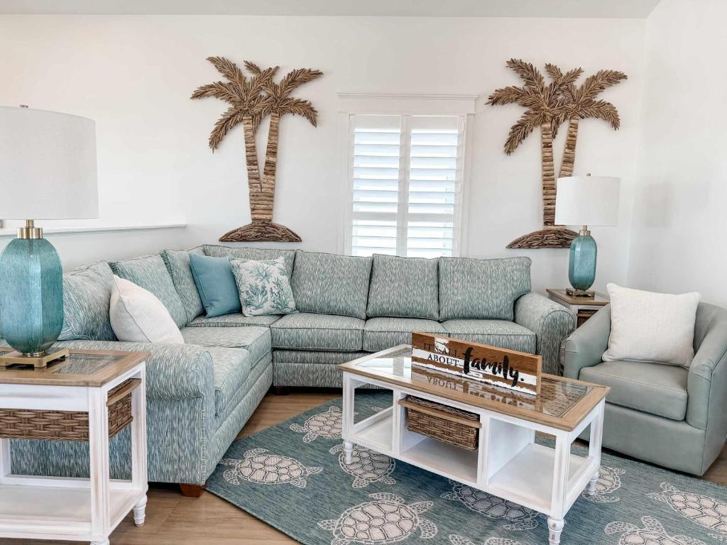 a living room with a blue couch and two palm trees at Serenity by the Sea St George Island Pool Home in Eastpoint