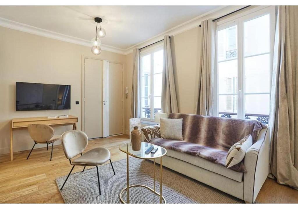 un salon avec un canapé et deux chaises et une télévision dans l'établissement Sublim new flat center of Paris Opéra Madeleine, à Paris