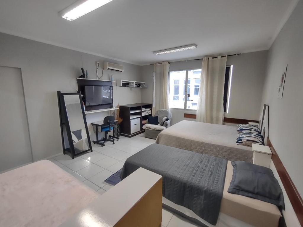 フロリアノポリスにあるApto studio no Centro de Floripa 201のベッド2台、机、テレビのある寝室
