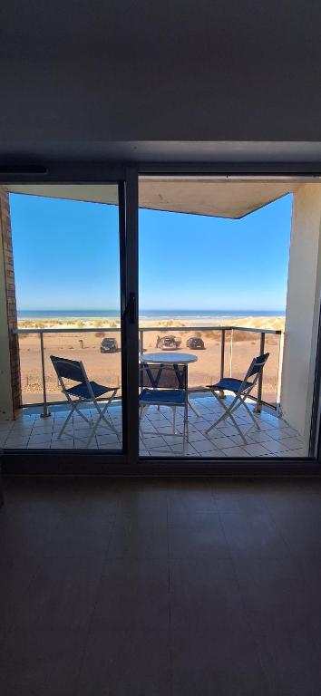 Elle offre une vue sur une terrasse avec une table et des chaises. dans l'établissement Face Mer, à Fort-Mahon-Plage
