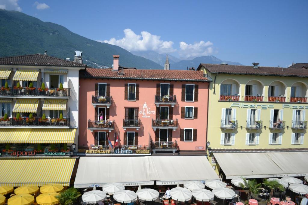 eine Gruppe von Gebäuden mit Tischen und Sonnenschirmen in der Unterkunft Al Faro in Ascona