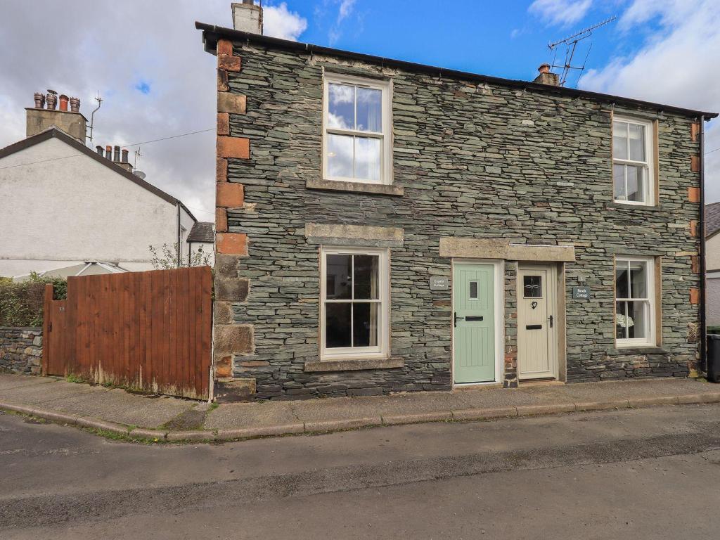 a stone house with a green door on a street at Capella Cottage in Keswick