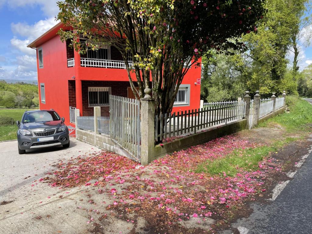 ein vor einem roten Haus mit Blumen geparktes Auto in der Unterkunft As Neveiras in Millerada