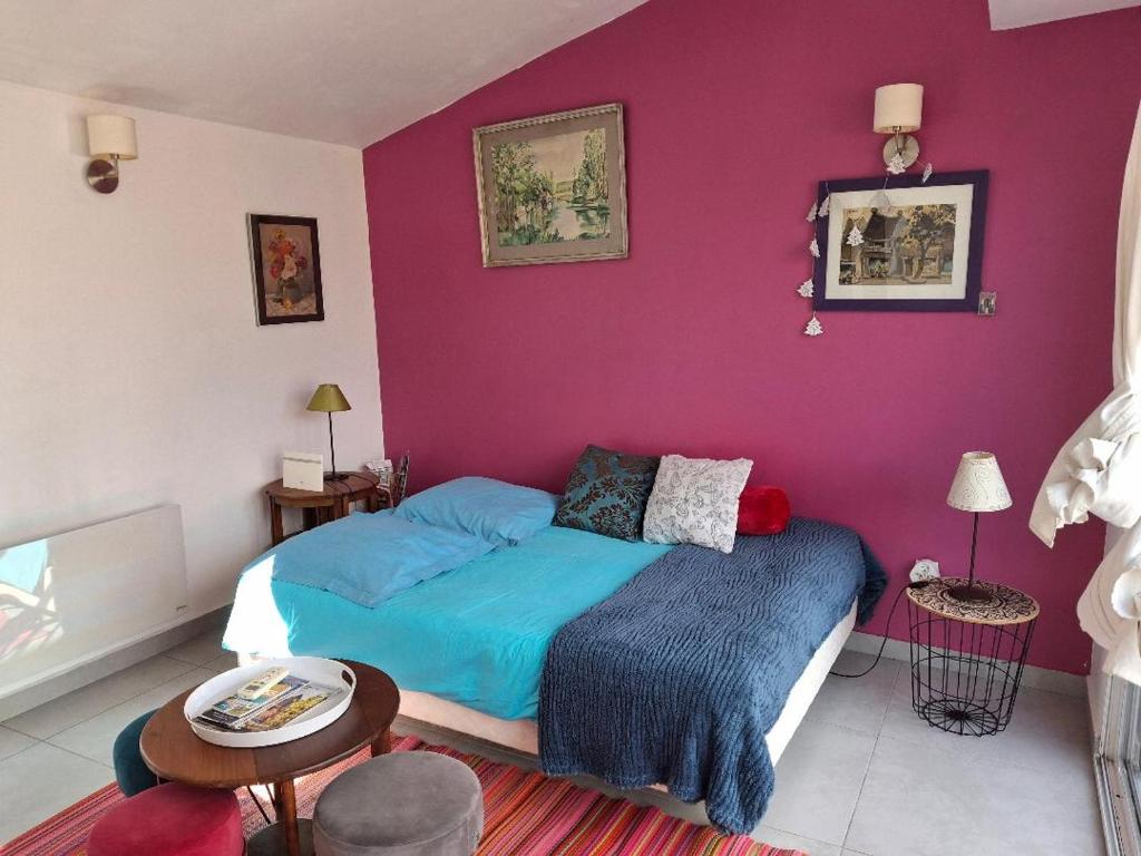 - une chambre avec un lit et un mur violet dans l'établissement Le studio perché, à Carcassonne