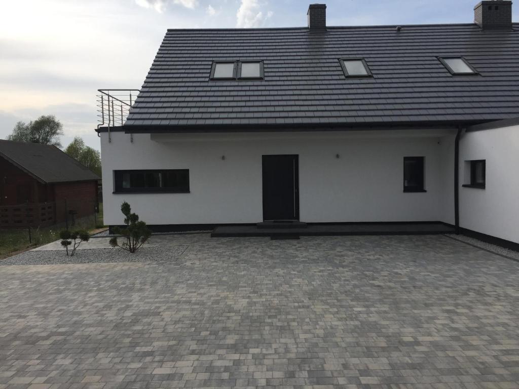 a white house with a black roof and a courtyard at Villa WoW in Zastań