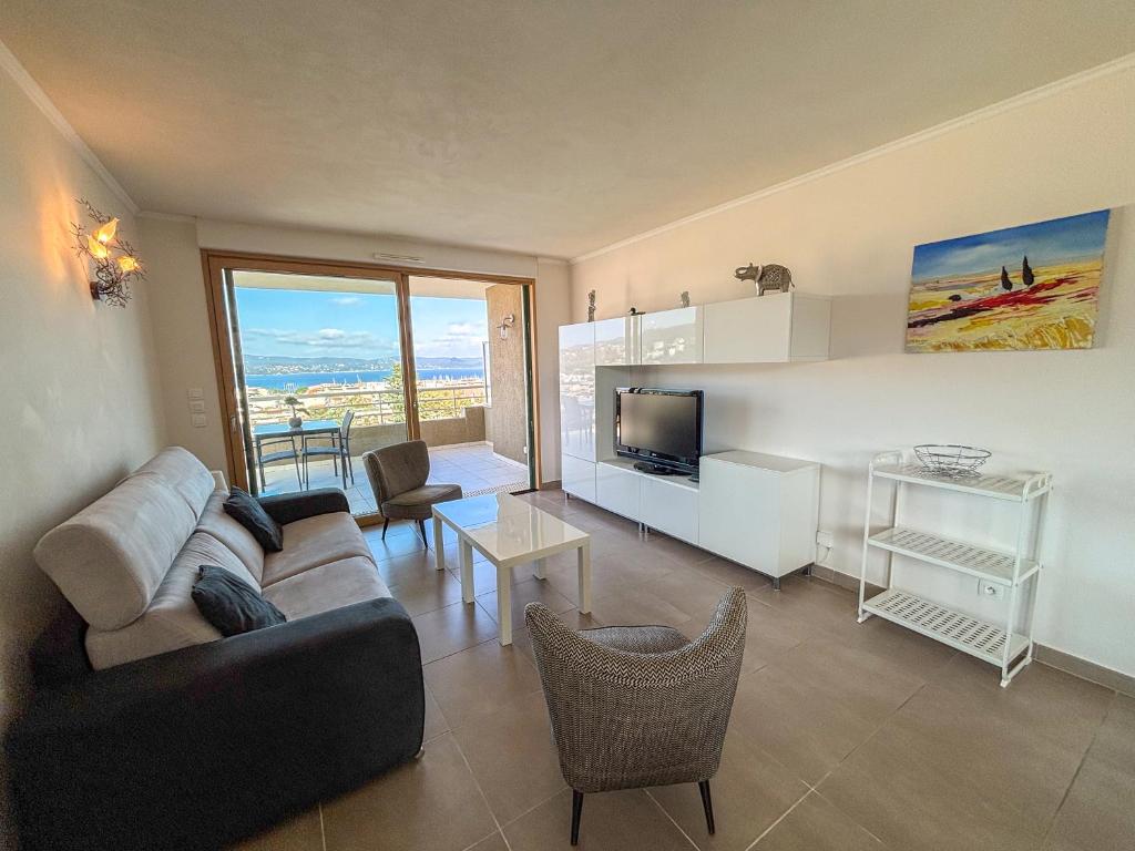 un salon avec un canapé, une télévision et une table dans l'établissement Azura - Appartement Climatisé 2 Chambres Terrasse Vue Mer avec Parking Privé Gratuit, à Cavalaire-sur-Mer